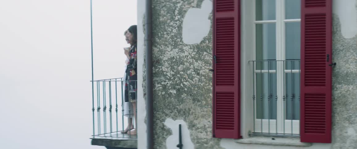 Two women stand out on a balcony