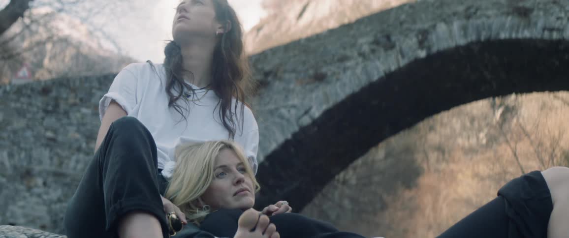Two women rest against a rock