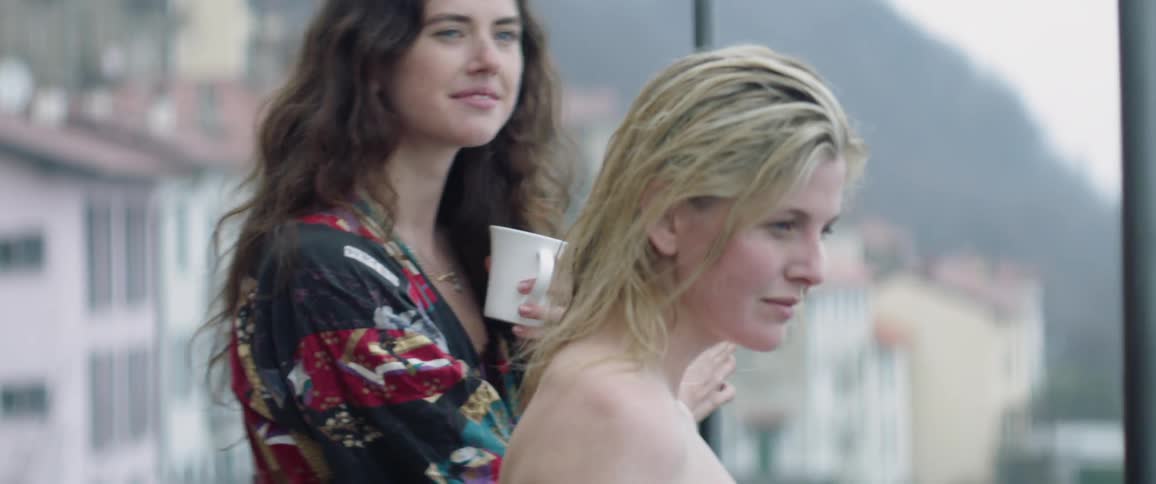 Two women have drinks on a rooftop