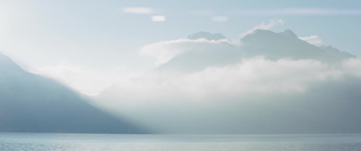 Sun shines over a mountain and body of water