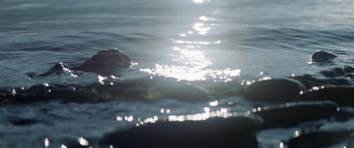 Sun shines over flowing water and rocks