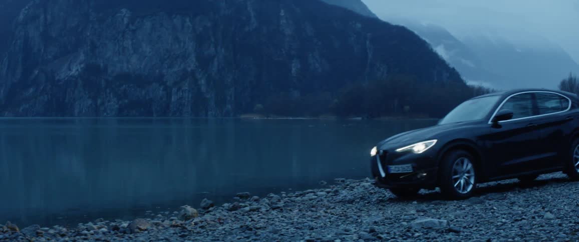 A car parks next to a mountain lake in the rain