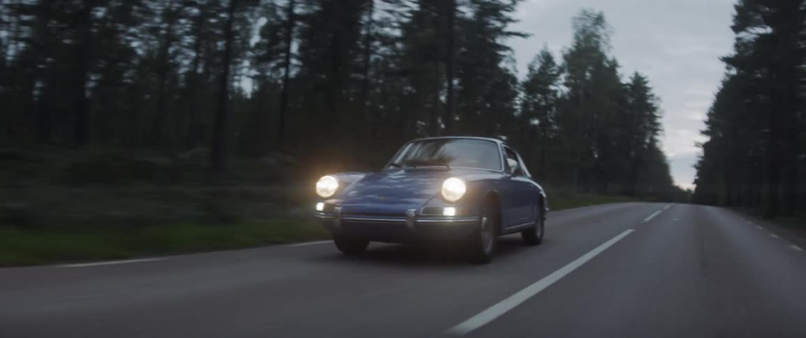 An old sports car drives on the rural road at night