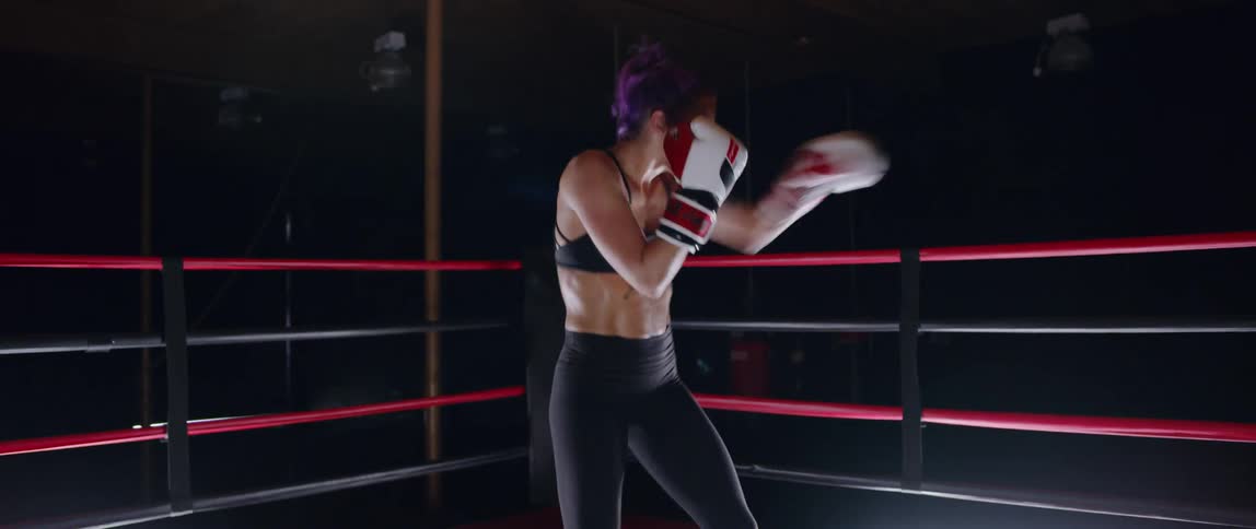 Woman stands in a boxing ring practicing punching