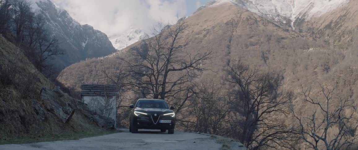 The car drives around the road near the mountain