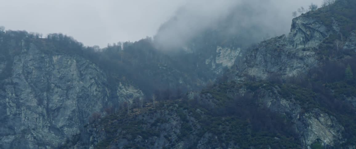 Fog hovers low on top of mountains on a cloudy day