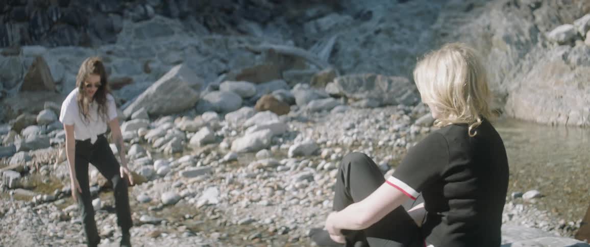 Women on beach take off their shoes and socks