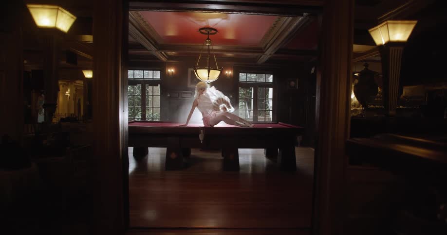 Woman sits on a pool table posing while holding a fan