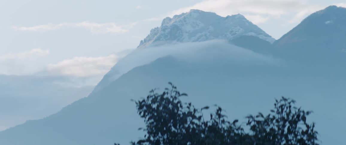 Clouds touch snow covered mountain