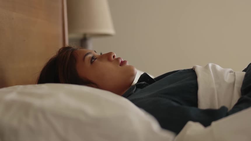 A woman is laying on a bed thinking