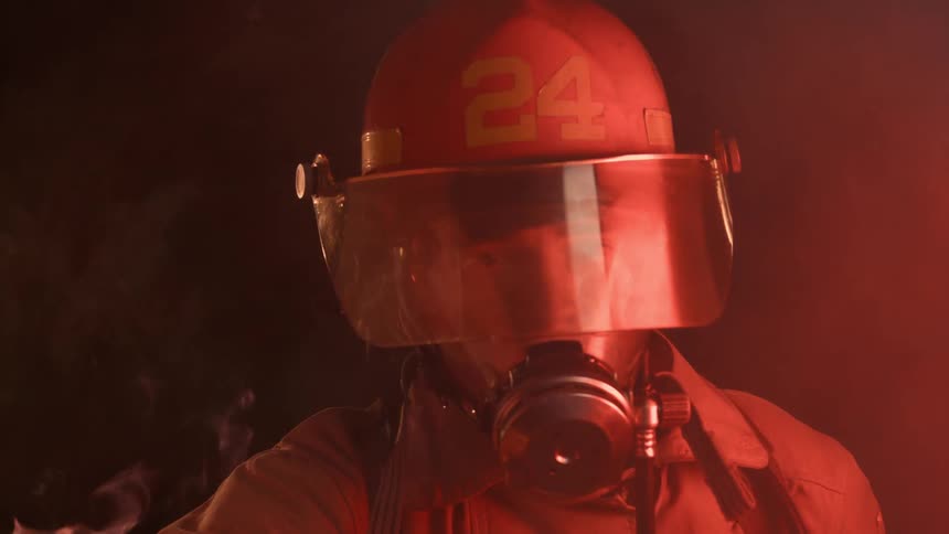 Flames rise behind a firefighter