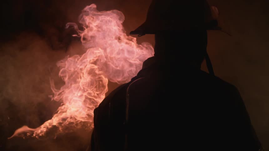 A firefighter stands near the blaze