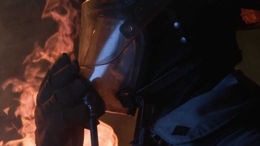 Firefighter wearing mask stands near flames