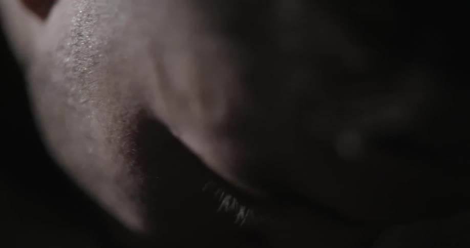 A man leans his head in a dim room