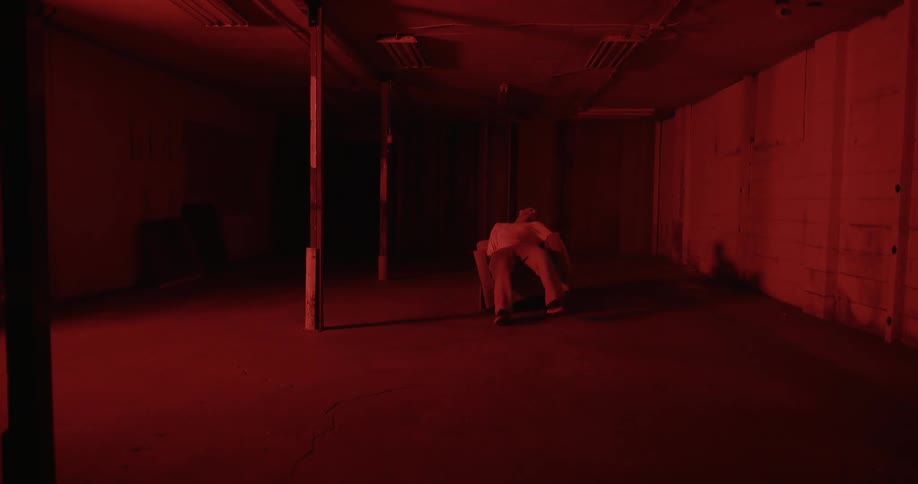 A man sits down in a red lit room