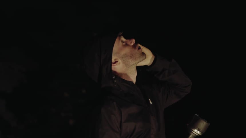 Man stands in the dark looking around and talking on a phone