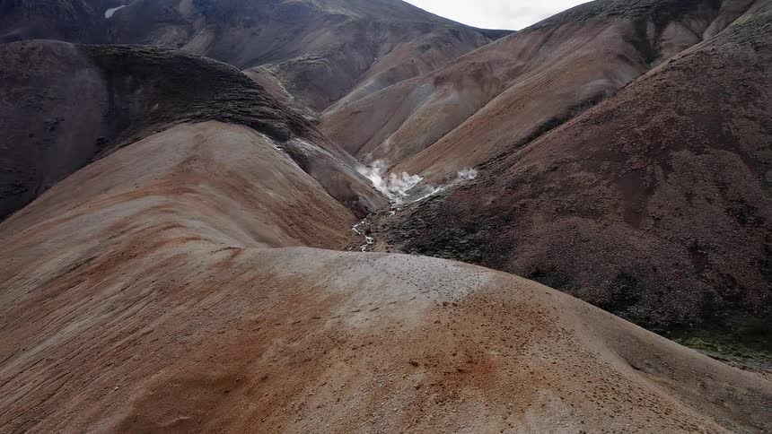 Steam pours from between the rolling hills