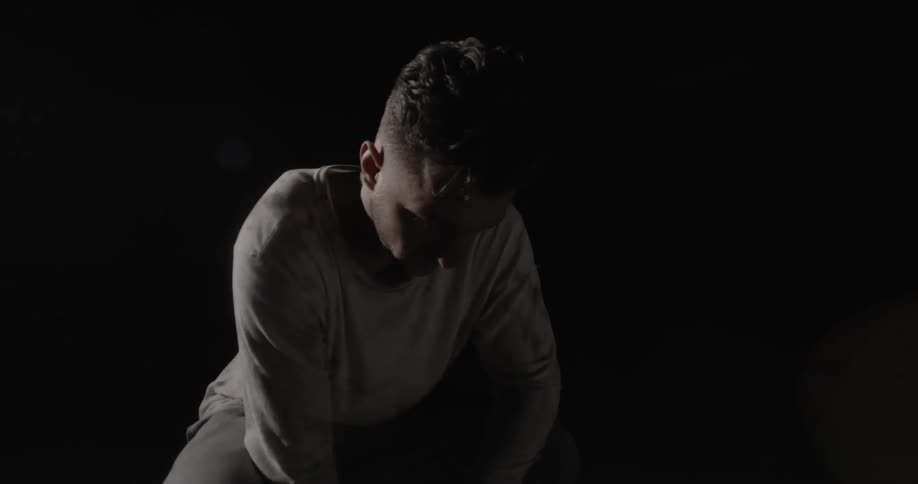 A man is crouched in the dark