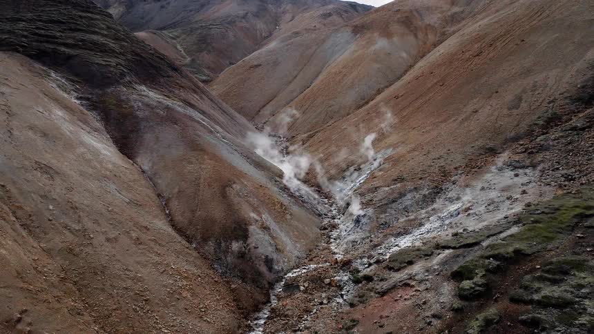 Steam rises up from the rocky mountain ground