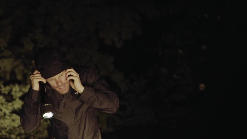 A man searches outside at night with a flashlight