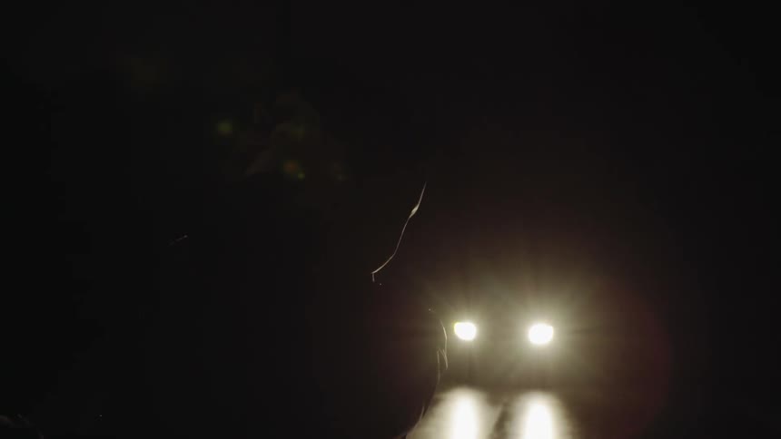 Man on cell phone at night standing in front of a car