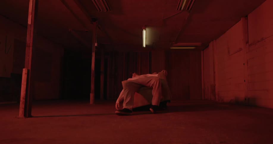 A man is lying slumped on a slab in a room with a flashing light