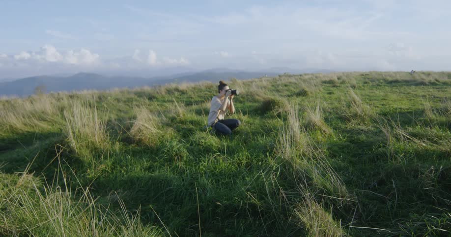 A woman takes photographs in the field