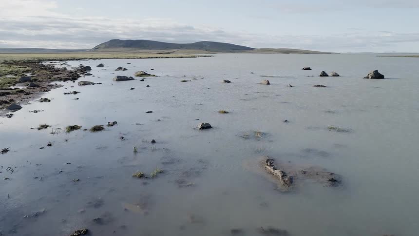 Rocks sit in the lake under a cloudy sky