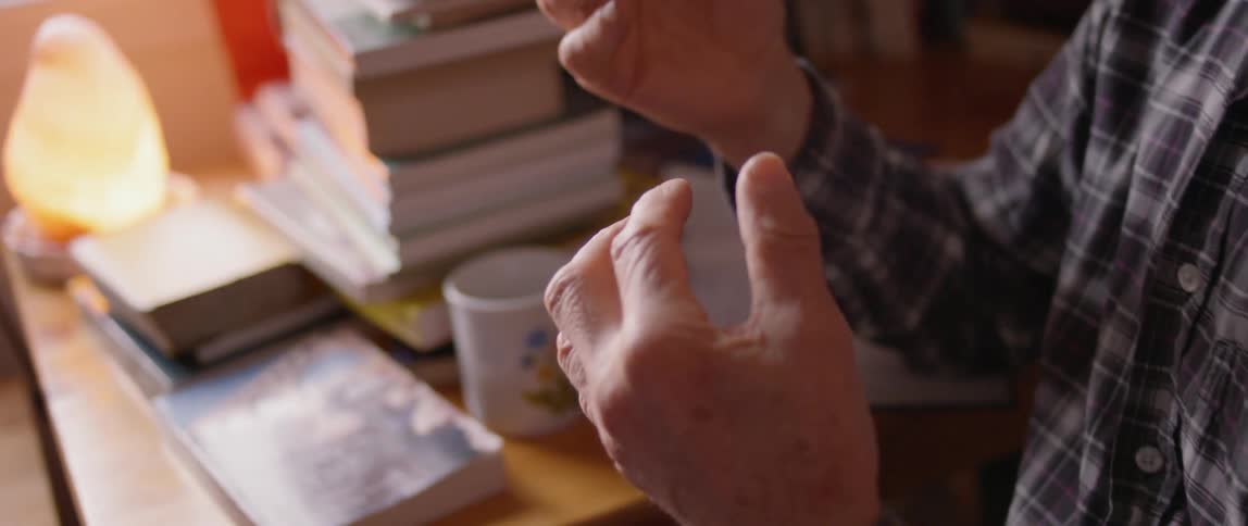 A man talks next to stacked books