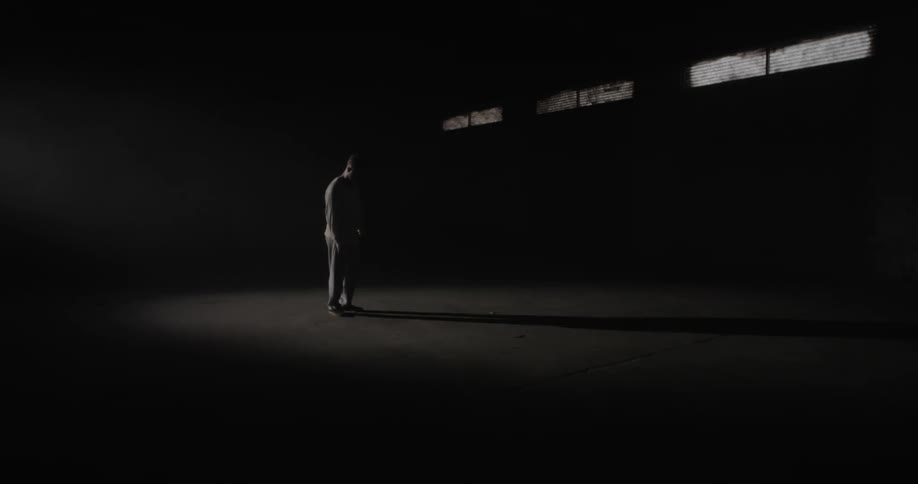 The person stands alone in the long dark room