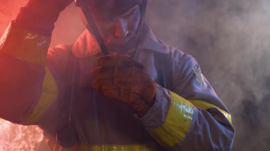 Firefighter putting on his helmet near fire