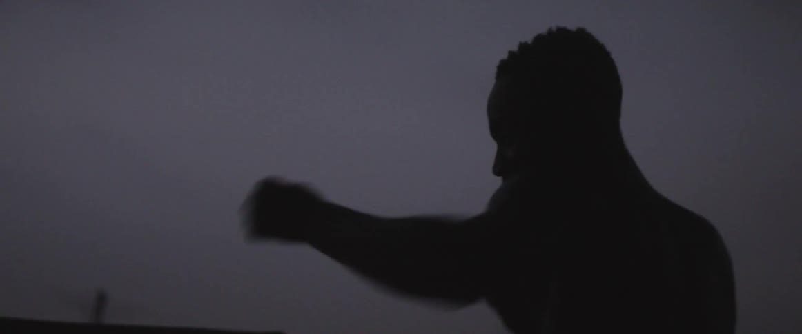 A man shadow boxes outside at night