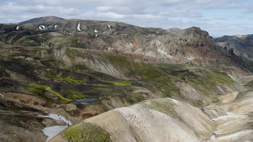 The hills are covered with grass and some snow