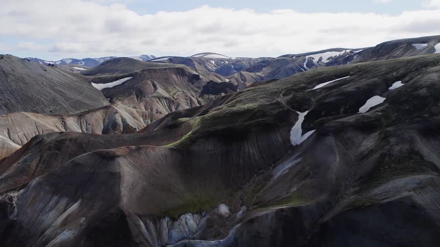 Clouds float above remote mountains and hills