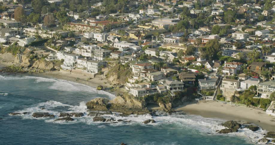 Ocean waves are crashing onto shore at beach town on sunny day
