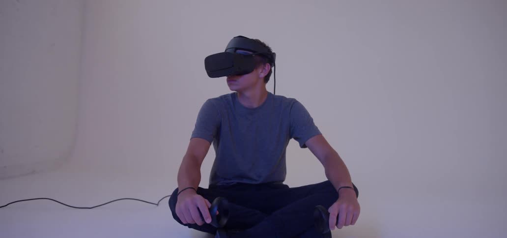 A boy sits in an empty room wearing virtual reality goggles