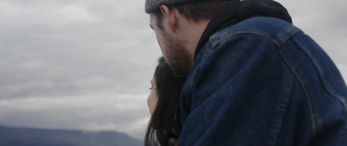 A man and woman look out over the lake together