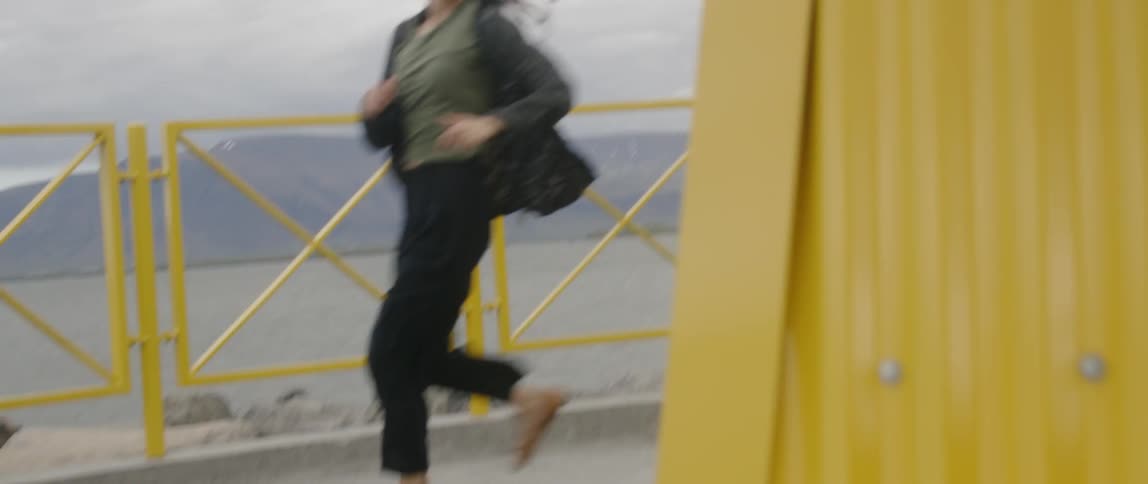Man chases a woman behind a yellow container
