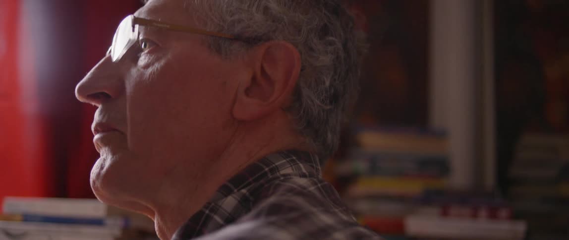 A man talks near stacks of books