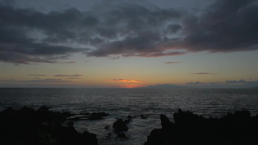 Timelapse of a sunset as seen from a rocky shore