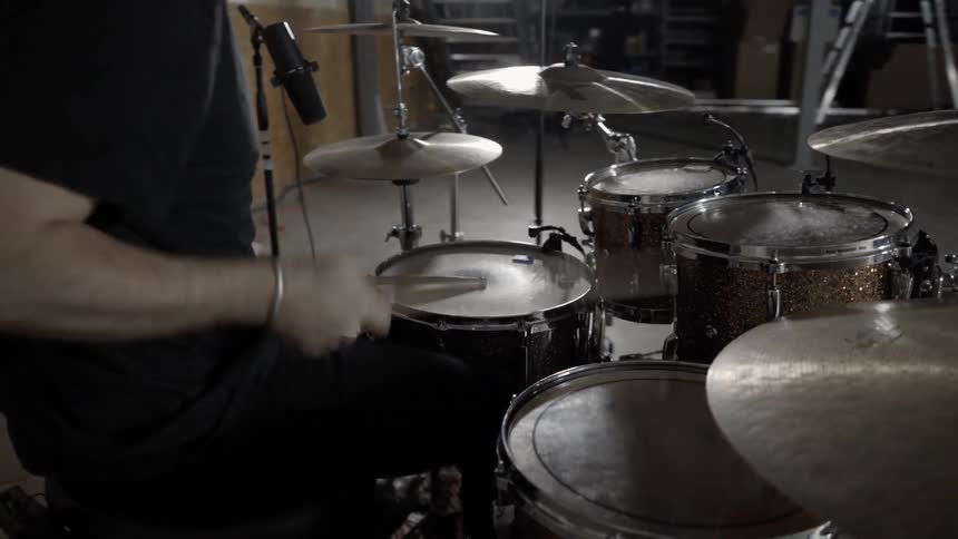 A man is playing drums under flashing lights