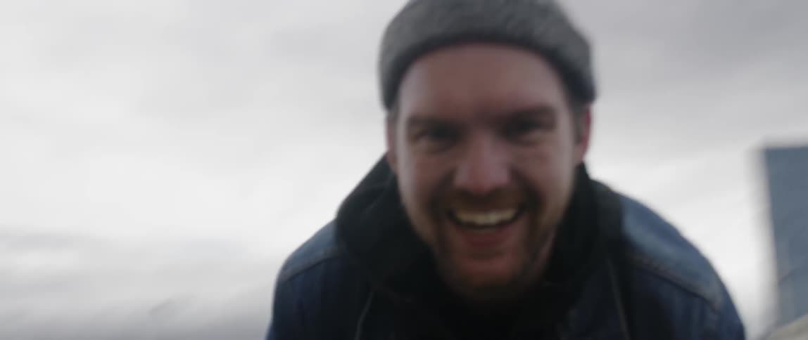 A man is teasing and playing with something in front of him outside under cloudy skies