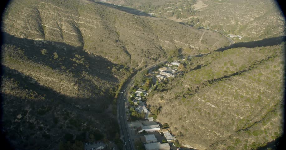 Cars drive by buildings in mountains