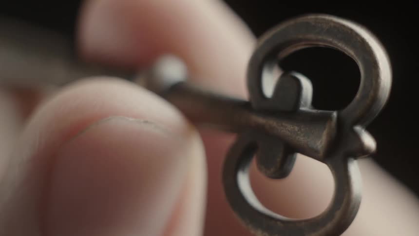 A person twirls an old key in their fingers