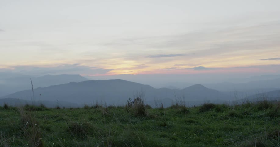 Clouds float above rural mountains at sunset