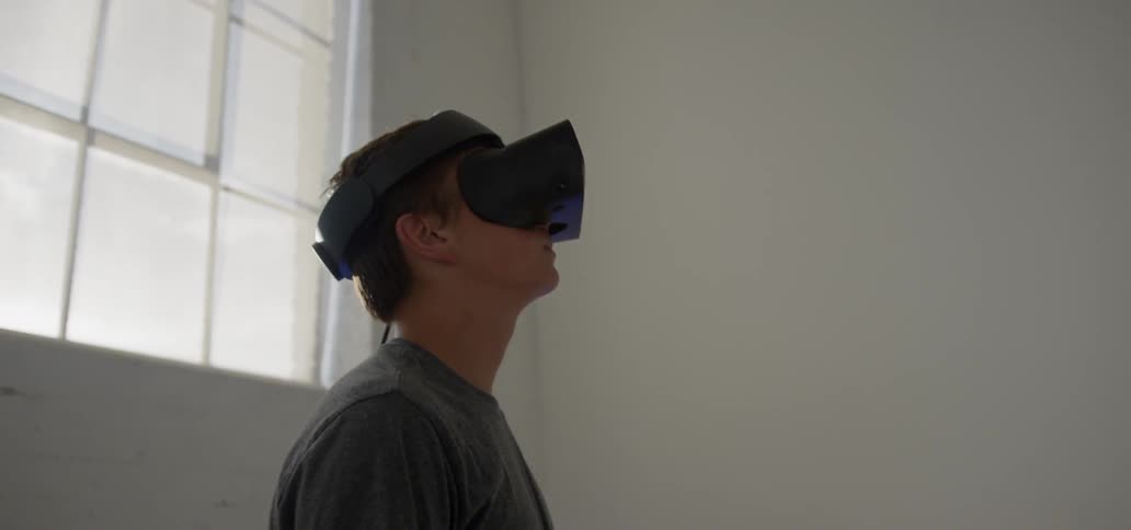 A boy is using a virtual reality headset inside in daylight