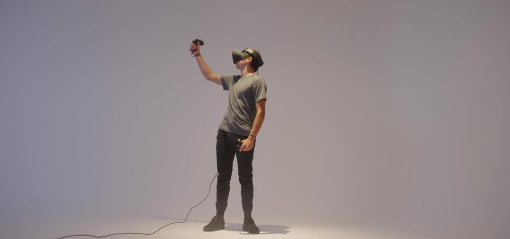 Man standing in an empty room wearing a vr mask and holding paddles