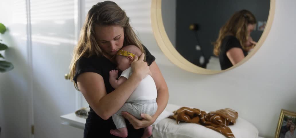 A woman rocks her baby in the room