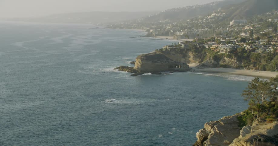 The waves crash against the rocks of the coastal town