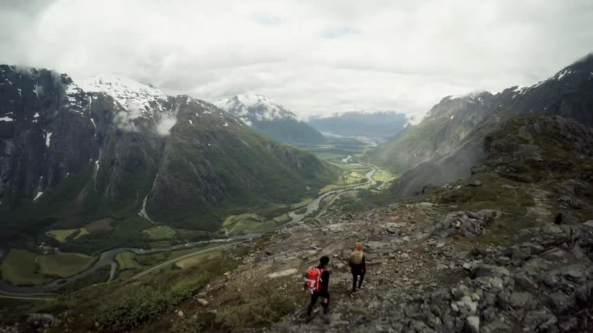 Two people hike mountains during the day